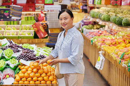 水果店内中年妇女挑选橘子背景图片