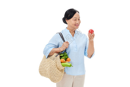 中老年买菜阿姨手拿番茄背景图片