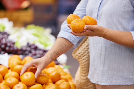 水果店传单中年女性挑选橘子特写背景