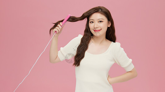 韩系美女使用夹板给头发做造型背景图片