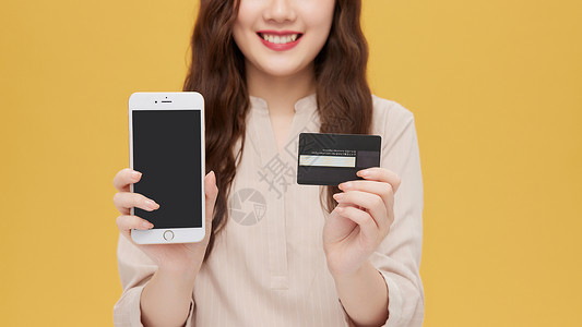 青年女性手拿信用卡和手机特写图片