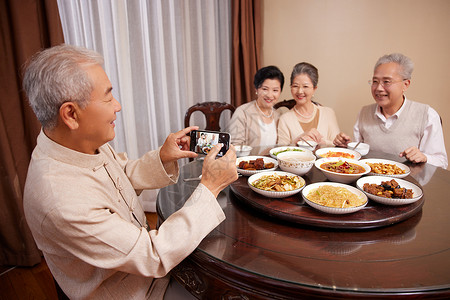 老友聚会一起吃饭使用手机拍照图片素材