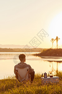 年轻男生坐在湖边看夕阳背影高清图片