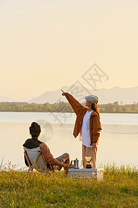 在野外郊游露营的人年轻情侣傍晚在湖边聊天背景