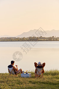 夕阳湖边年轻情侣湖边享受大自然背景