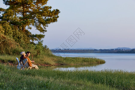 在野外郊游露营的人年轻人傍晚在湖边聚会聊天背景