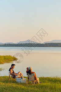 夕阳湖边年轻情侣旅行湖边享受大自然背景