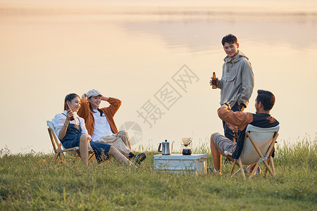 夏天喝啤酒年轻人傍晚在湖边聚会聊天背景