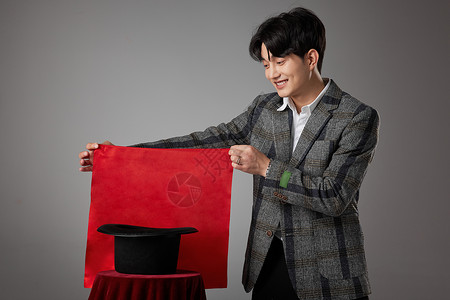 男性魔术师手拿红色方巾正在变魔术背景图片