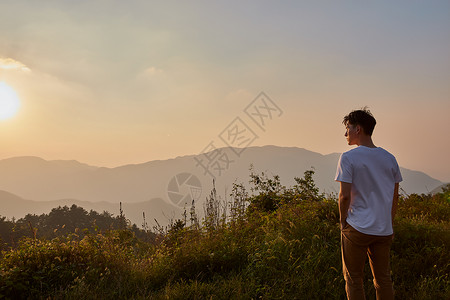 年轻男生山顶看落日背影假期高清图片素材
