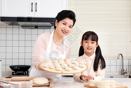 老人与孩子奶奶与孙女厨房里展示手工饺子背景