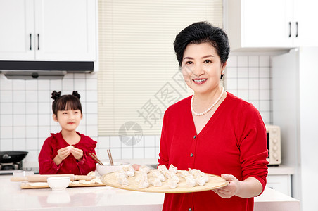 端着美食的奶奶厨房里奶奶端着包好的饺子背景