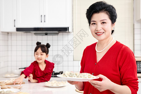 煮饺子女人厨房里奶奶端着煮好的饺子背景