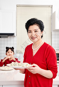 端着美食的奶奶厨房里奶奶端着煮好的饺子背景