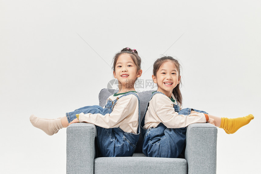 亲密双胞胎小姐妹沙发上快乐陪伴图片