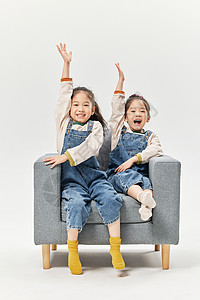 双胞胎小女孩居家沙发上举手图片