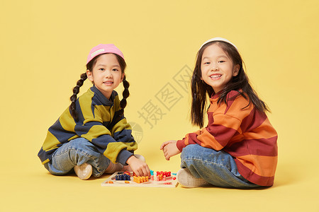 双胞胎小女孩坐地上下跳棋背景