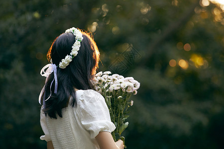 少女如花夕阳下拿着花的少女背影背景