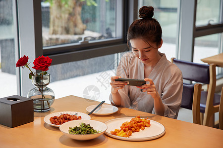 青年女性吃饭用手机拍照记录美食背景