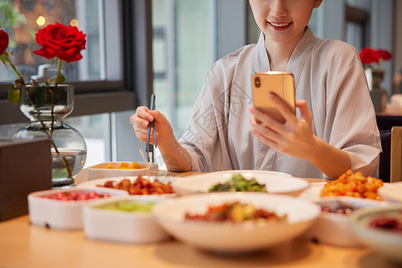 女生美食青年女性在汤泉馆吃饭玩手机特写背景