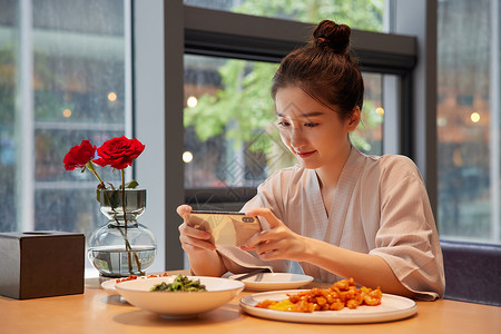 青年女性吃饭用手机拍照记录美食图片素材