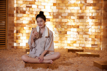 青年女性在盐蒸房玩手机背景图片