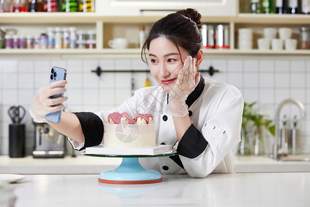 女烘焙师拿手机与蛋糕自拍图片