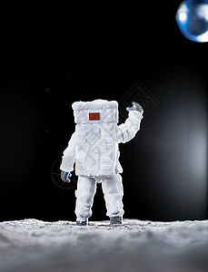 宇航员站在月球表面向地球挥手高清图片
