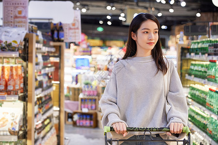 青年女性推手推车逛超市购物图片