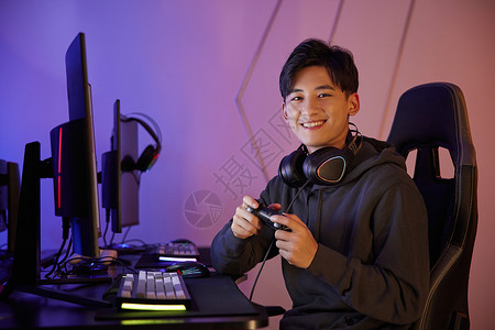 青年男性坐电脑前拿游戏手柄打游戏图片