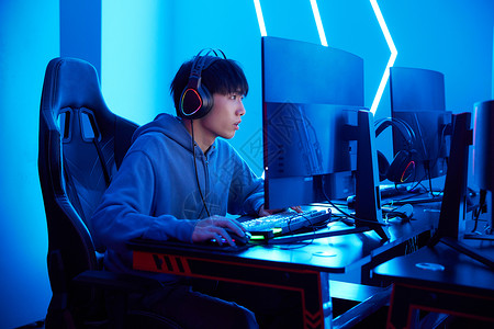 坐椅子上男孩年轻人坐电脑前打网络游戏背景