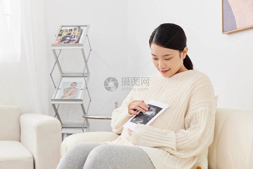 孕期妈妈居家坐沙发上看婴儿B超图像图片