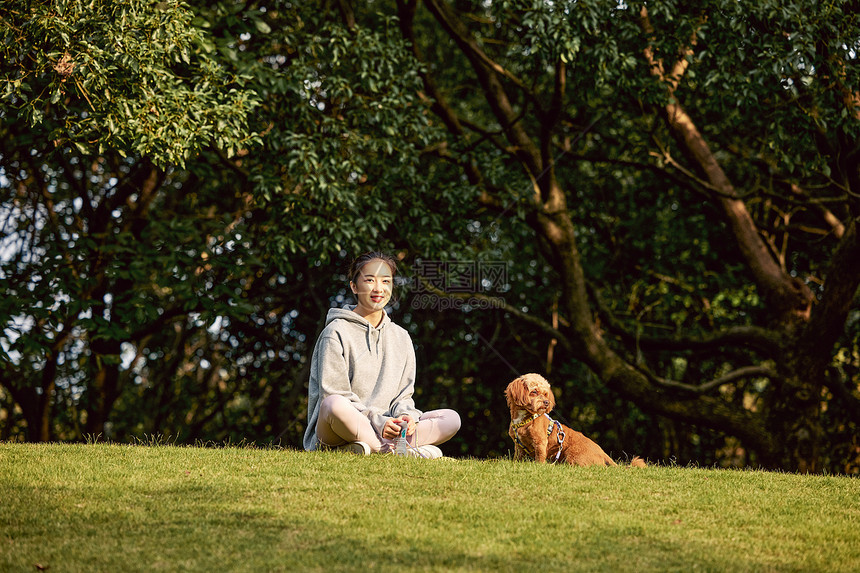 空旷草地上休息的美女和泰迪图片