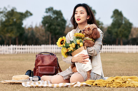 坐在秋日草地上的美女和泰迪图片素材