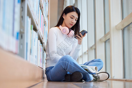 女学生在图书馆看书玩手机图片