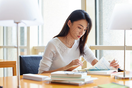 女大学生在图书馆翻阅学习资料图片