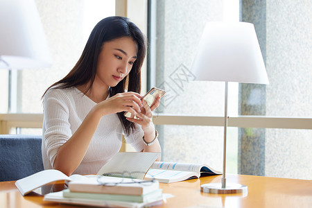 女学生图书馆学习使用手机查资料图片