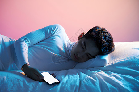 睡眠科技男青年夜晚拿着手机睡觉背景