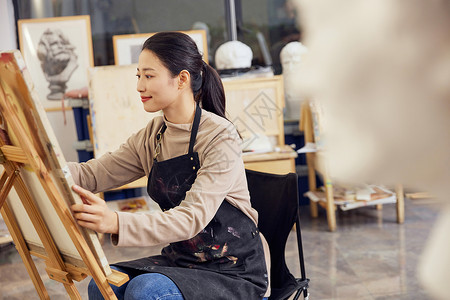 素描培训班招生女性坐在画室画石膏像背景