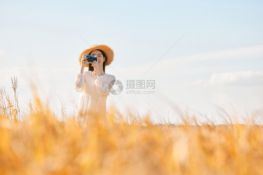 拿着照相机站在稻田里的女性图片