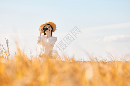 拿着照相机站在稻田里的女性图片素材