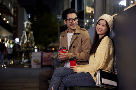冬日夜晚街边喝咖啡聊天的青年情侣形象图片