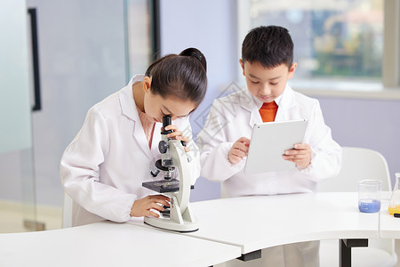 化学课小男孩给看显微镜的小女孩做记录背景