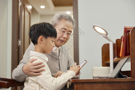 坐着吃瓜的爷孙孙子教爷爷使用智能手机背景