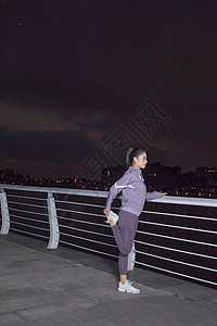 城市夜晚美女江边拉伸锻炼图片