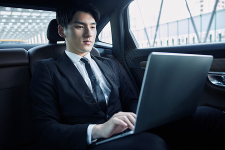 年轻白领坐在轿车里用笔记本电脑办公高清图片