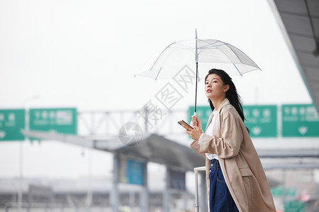 户外撑伞等车的女性背景图片