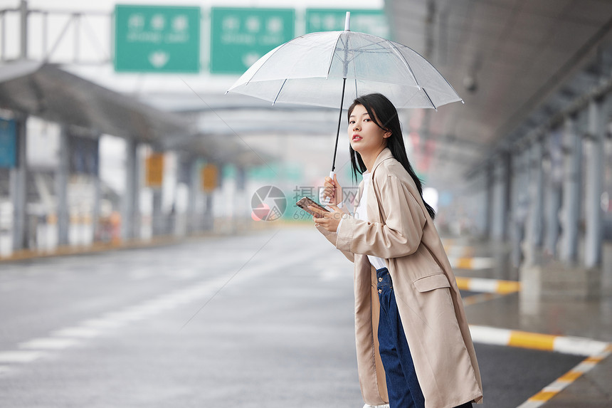 户外撑伞等车的女性图片