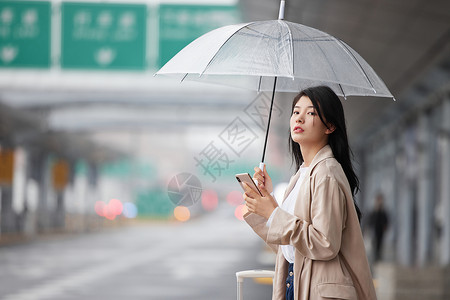 户外撑伞等车的女性背景图片