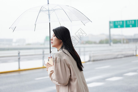 户外撑伞等侯的年轻女性背景图片